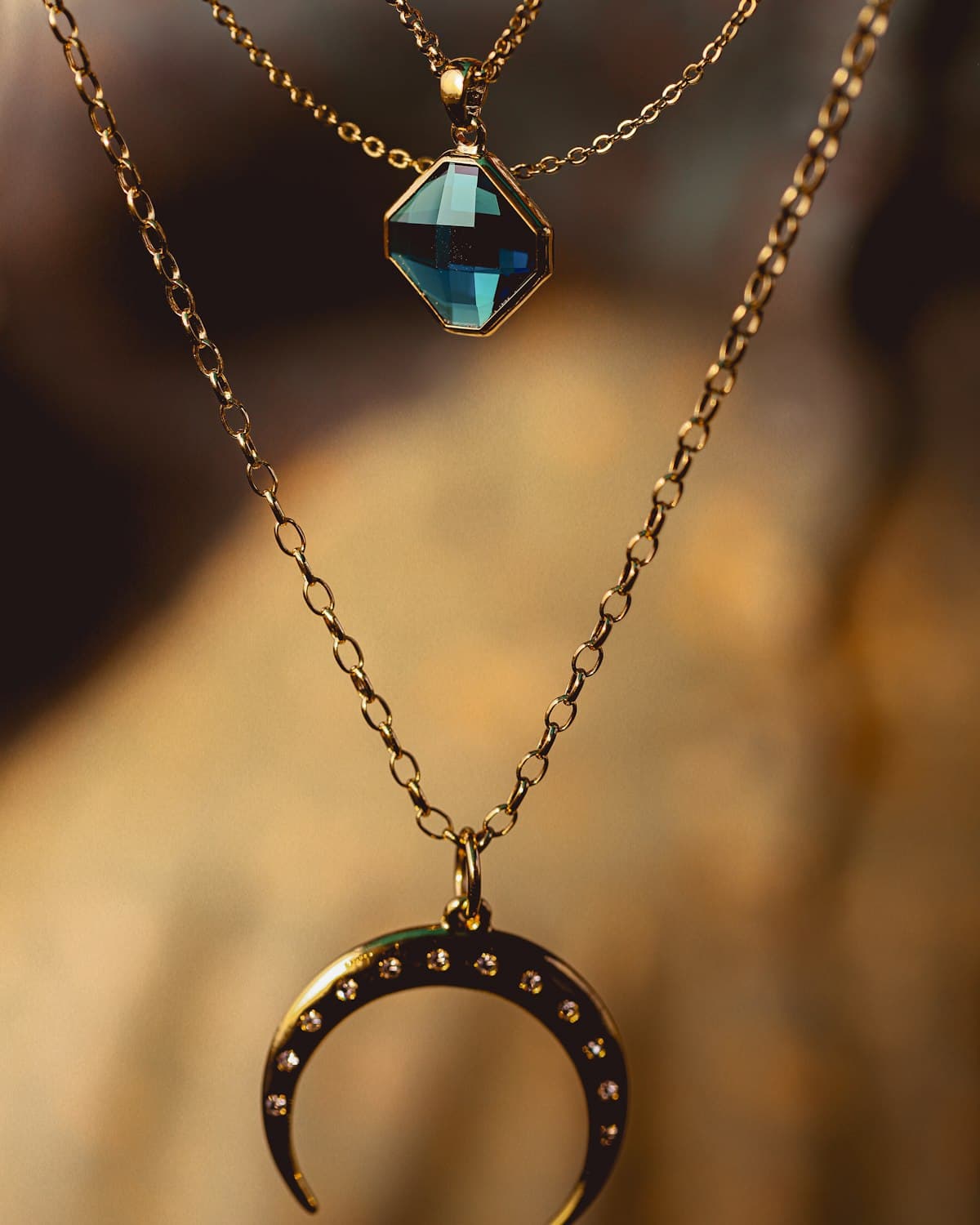 Layered gold necklaces with teal gemstone and crescent pendants