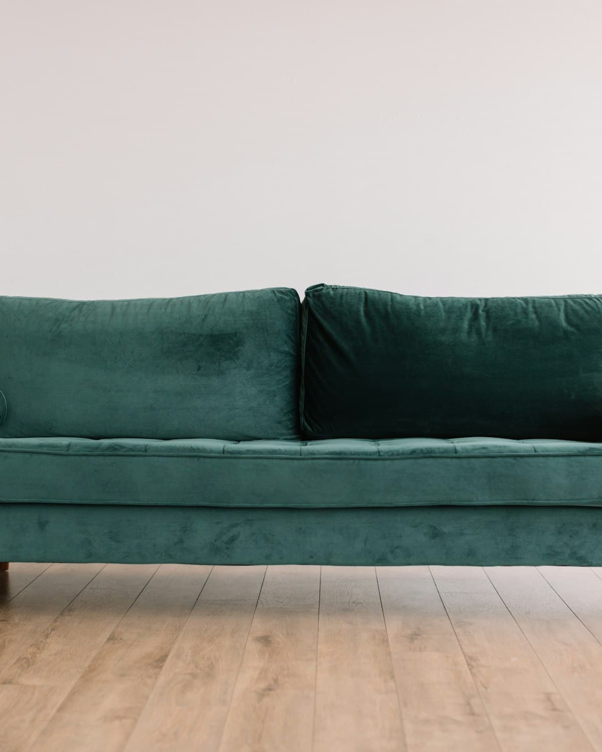 Forest green velvet sofa against a light wall and wood floor