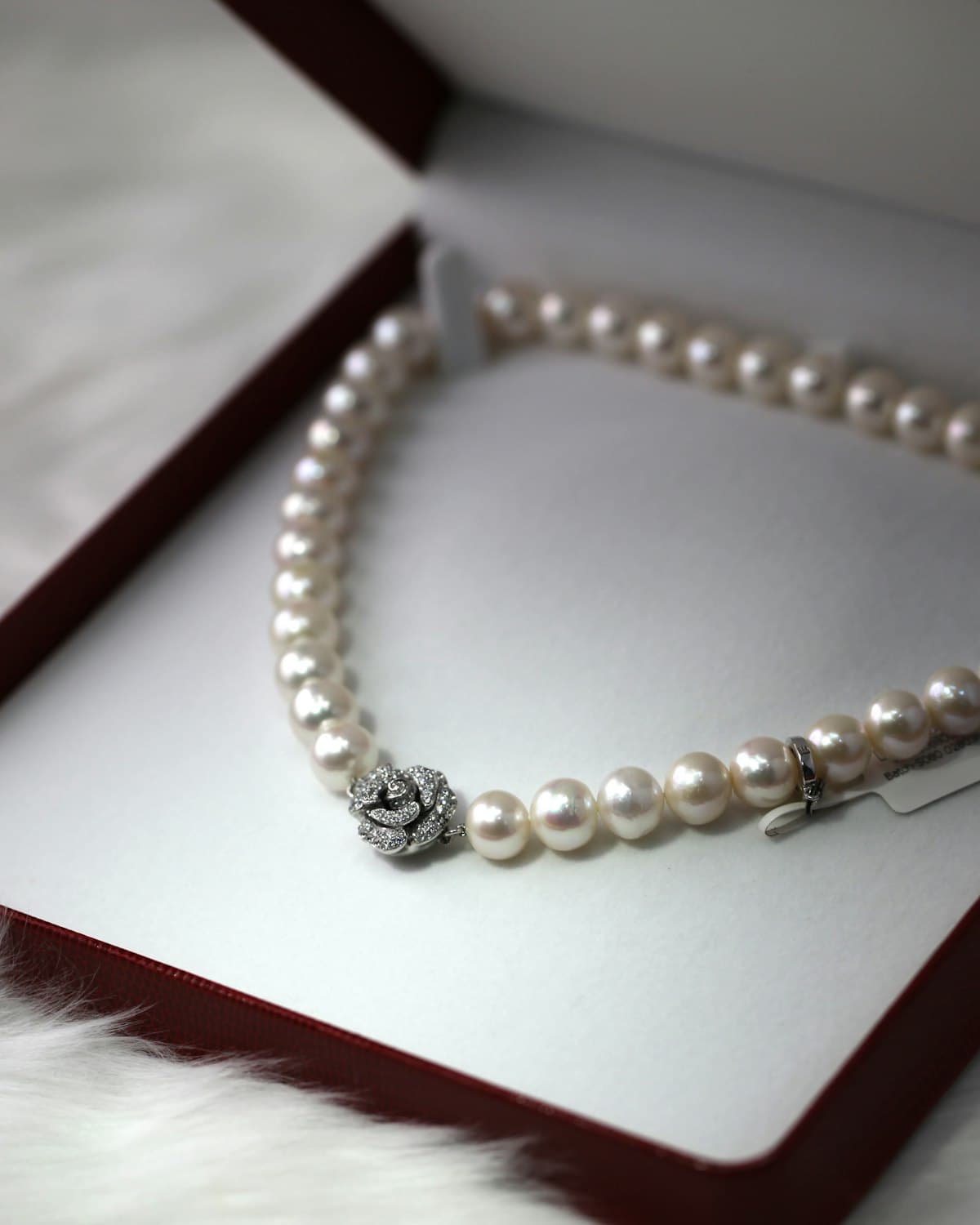 Pearl necklace with rose clasp displayed in an open jewelry box
